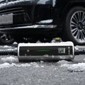 Ładowarka Besen BN70 w warunkach zimowych Kontroler przenośnej ładowarki do samochodu elektrycznego Besen BN70 leżący na śniegu przy samochodzie, ekran LCD aktywny