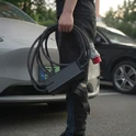 Przenośna ładowarka Besen BN60 - kompaktowa i lekka, zabierasz ją wszędzie Osoba trzymająca przenośną ładowarkę do samochodu elektrycznego Besen BN60 z wtykiem CEE 16A na parkingu przy samochodzie - kompaktowa i lekka ładowarka mobilna EV